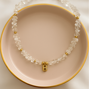 Necklace with clear beads and gold accents on a pink plate