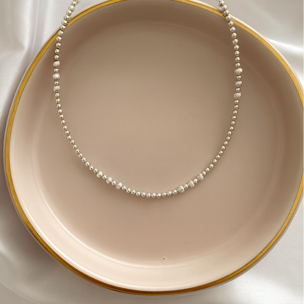 Load image into Gallery viewer, Necklace on a beige plate with a gold rim against a white background
